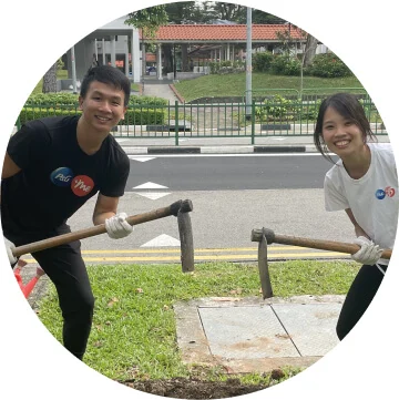 A man in a black t-shirt and a woman in a white t-shirt are holding axes and are smiling toward the camera.