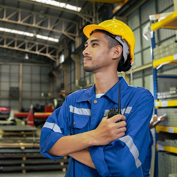 Man in an warehouse with crossed arms looking aside holding a walkie talkie