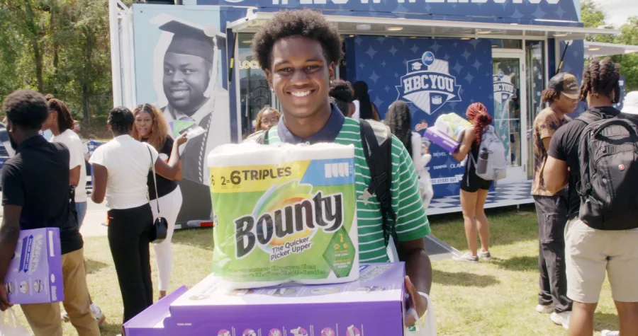 A young, black male college student holds Bounty paper towels.