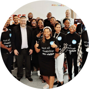 A group of people are posing for a group photo and are smiling towards the camera.