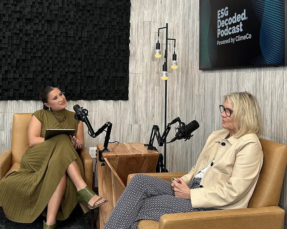 Two women with microphones sit together recording a podcast.