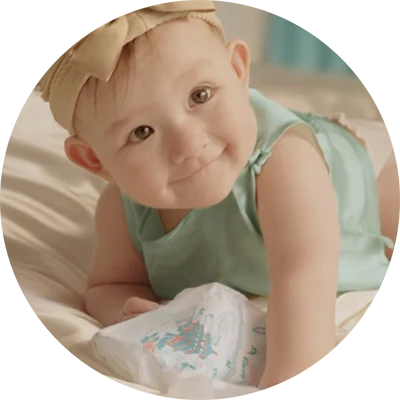 Baby crawling on a bed next to a Pampers diaper