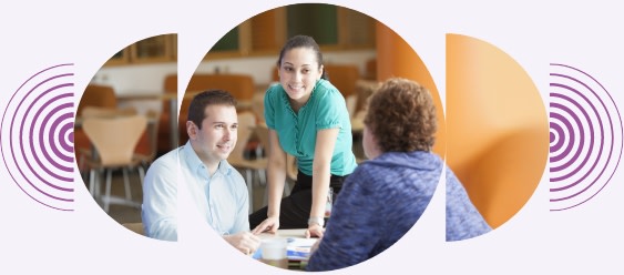 Two women and a man seated at an office table working together