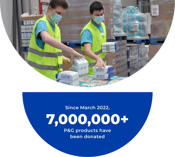 Two men wearing masks and high-visibility safety vests handle P&G products inside a warehouse