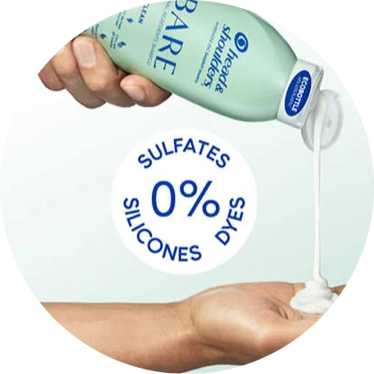 A hand squeezes a light green Head & Shoulders shampoo bottle while another hand catches the white liquid as it pours out of the spout. Blue text reads, "0% sulfates, silicones, dyes."