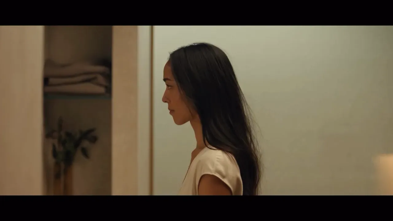 Woman with long dark hair looking at her reflection in a mirror.