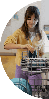 A teenage girl loads a dishwasher