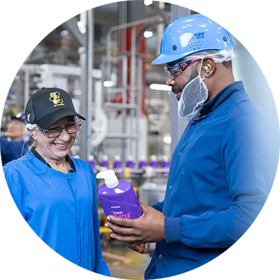 Two plant employees look at a P&G product near a manufacturing line.