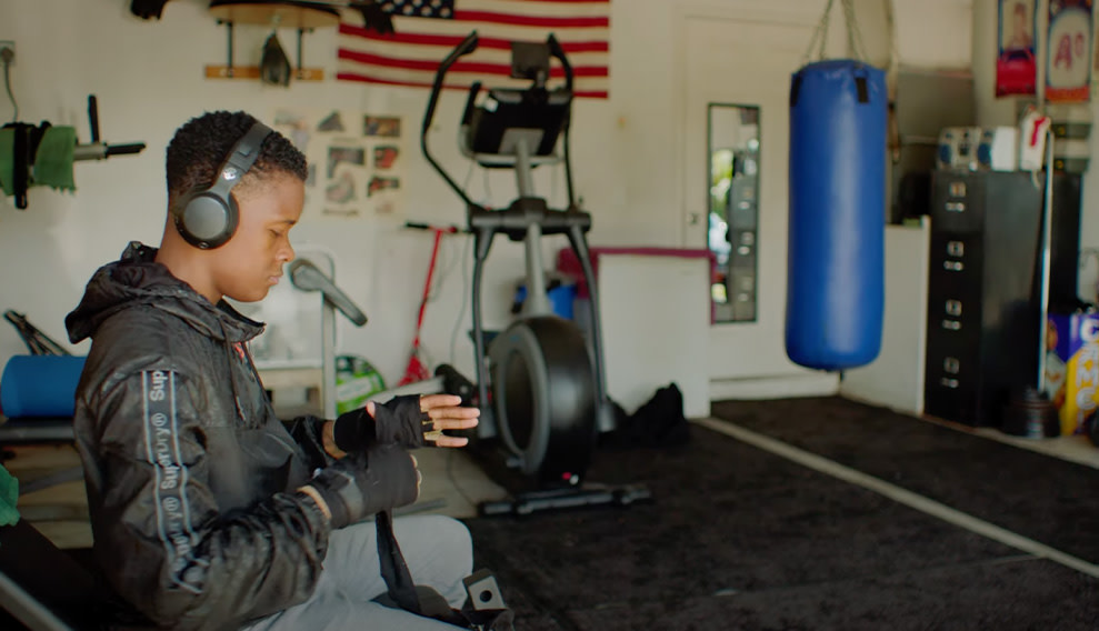 Teenager in a gym, wearing headphones, getting ready for a training session by wrapping his wrist