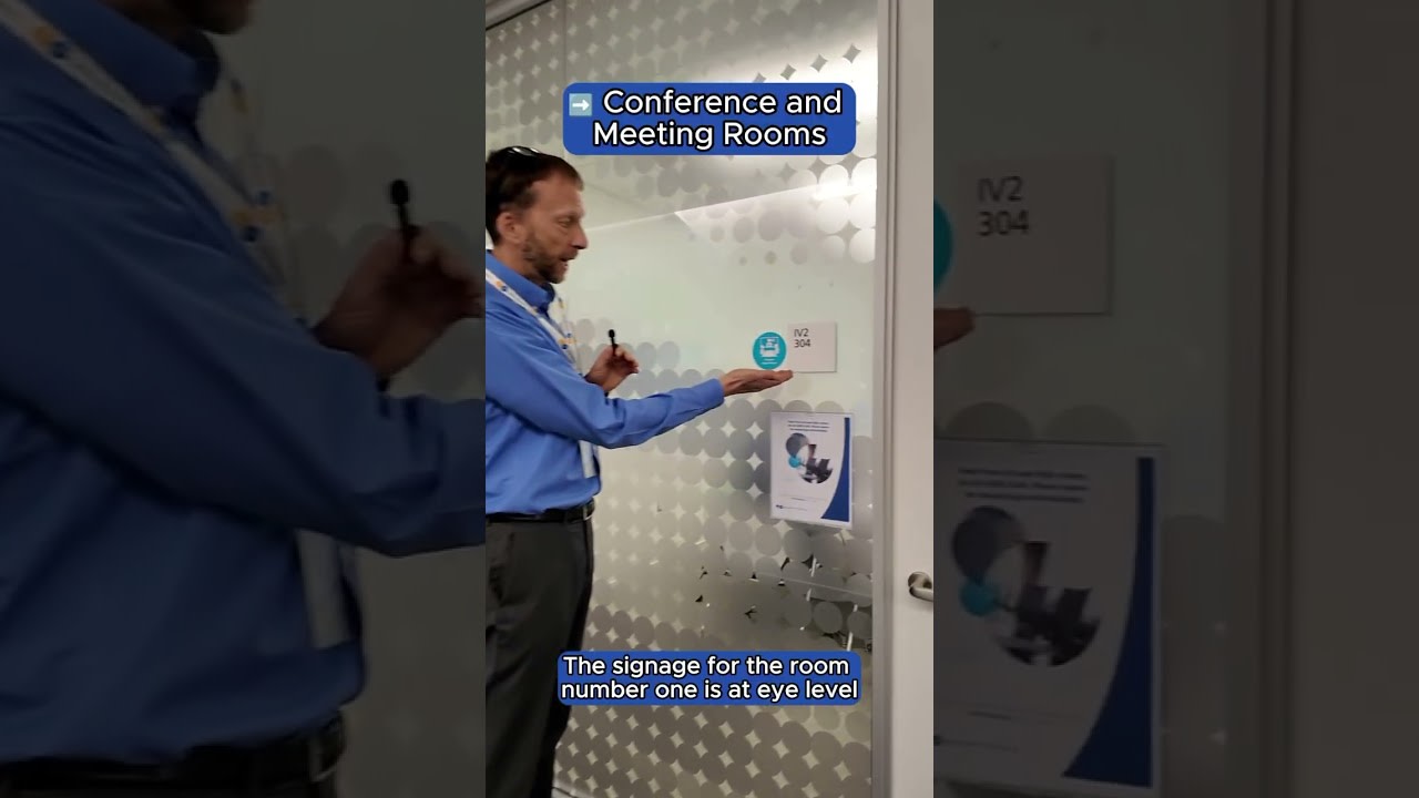 A tall man in a blue shirt and gray pants. 