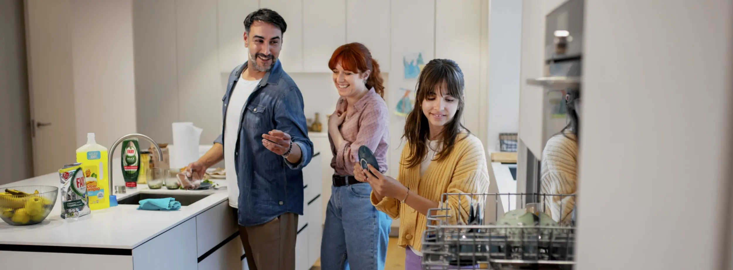 Man, woman and young girl are in kitchen washing and putting away dishes.