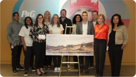 Eleven people are standing behind and next to a poster.