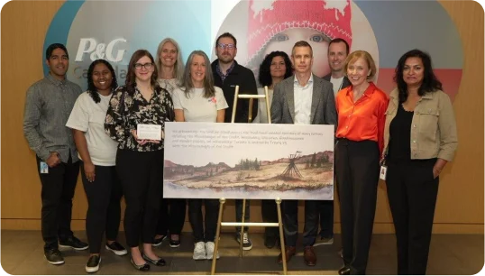 Eleven people are standing behind and next to a poster.