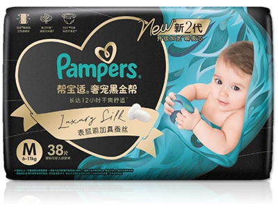 The front of a package of Pampers Prestige 'Luxury Silk' diapers, featuring a smiling baby wrapped in a flowing, silky fabric on a black and gold background.