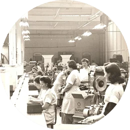 Several white women in uniforms are working in a Tampax factory during world war two. The image is in black and white.