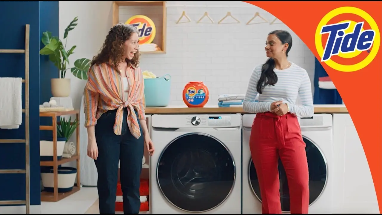 Two women in front of washing machines using Tide products