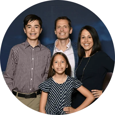 P&G employee Cecilia Colburn, her husband, son and daughter all smile at the camera with a dark backdrop behind them.