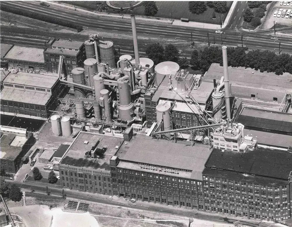 A black and white bird’s eye view of a large manufacturing facility with many towers and a building that says “Procter & Gamble.”
