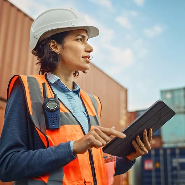 Woman dressed in safety gear standing in front of shipping containers