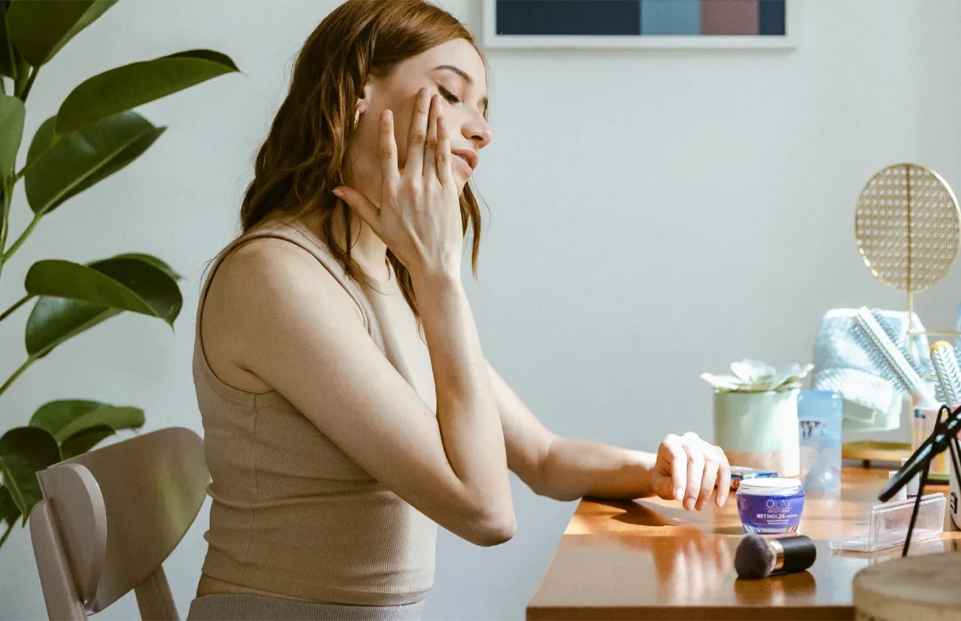 Woman seated at a desk with P&G personal‑care products arranged nearby.