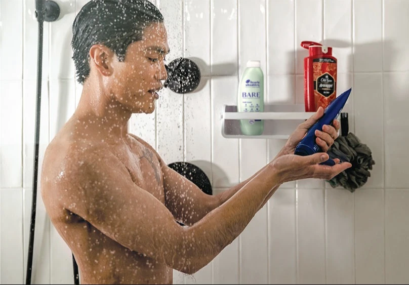 Man in shower squeezing shampoo into his hand