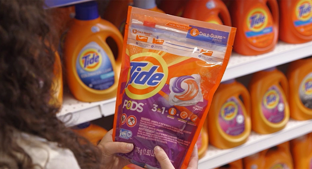 Person holding Tide Pods in front of product shelf