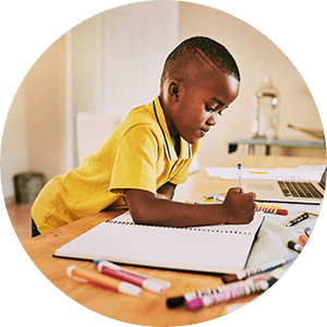 A boy writing his homework standing behind a desk