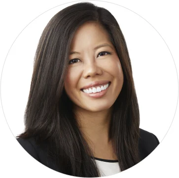 A woman with long brown hair is smiling towards the camera. 