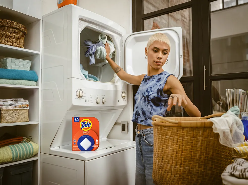 Woman doing laundry at home, handling clothing as part of her everyday laundry routine.