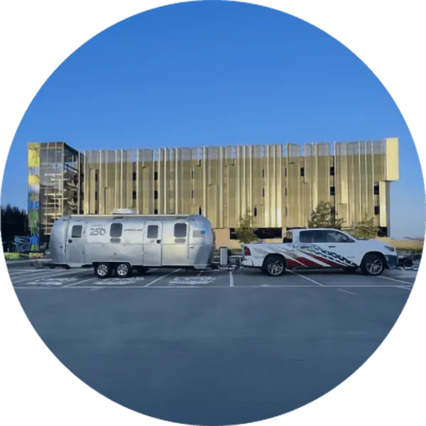 ilver trailer and pickup truck with P&G branding parked in front of a large industrial building