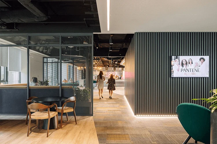 Two women walk down a wide hallway in office building.