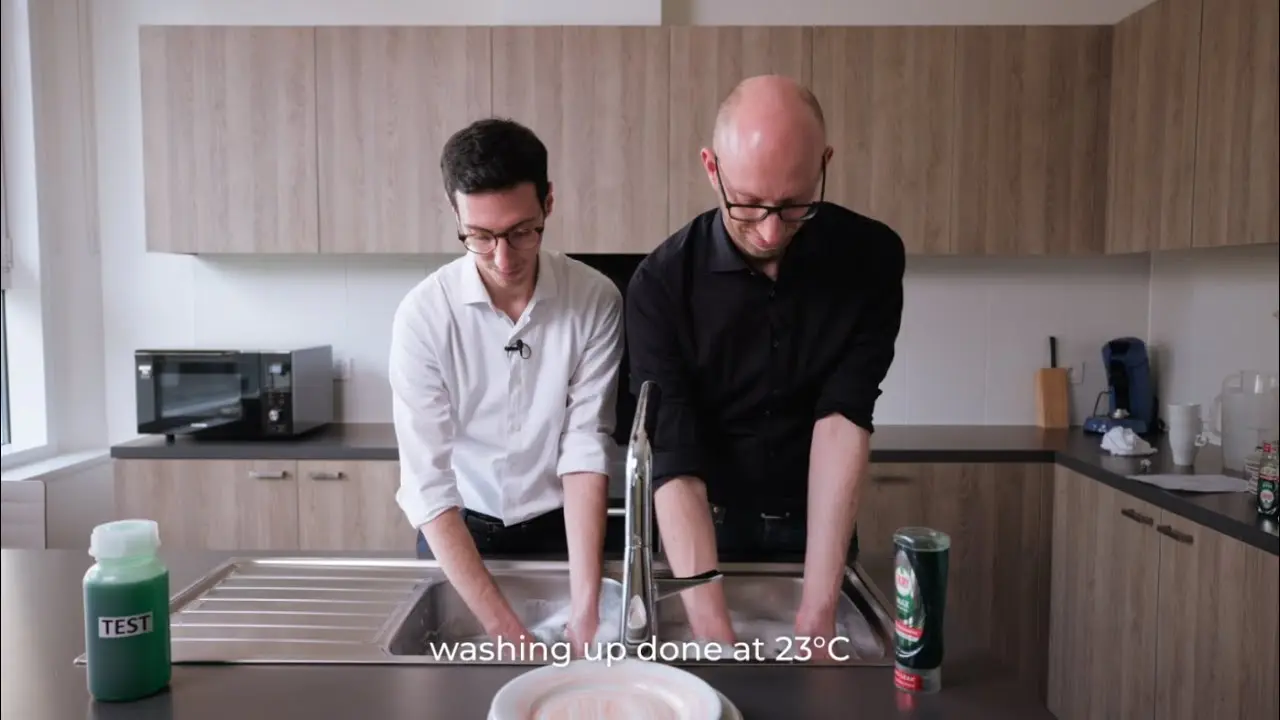 Two people washing dishes in the kitchen sink