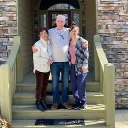 Three people standing on the house entrance stairs