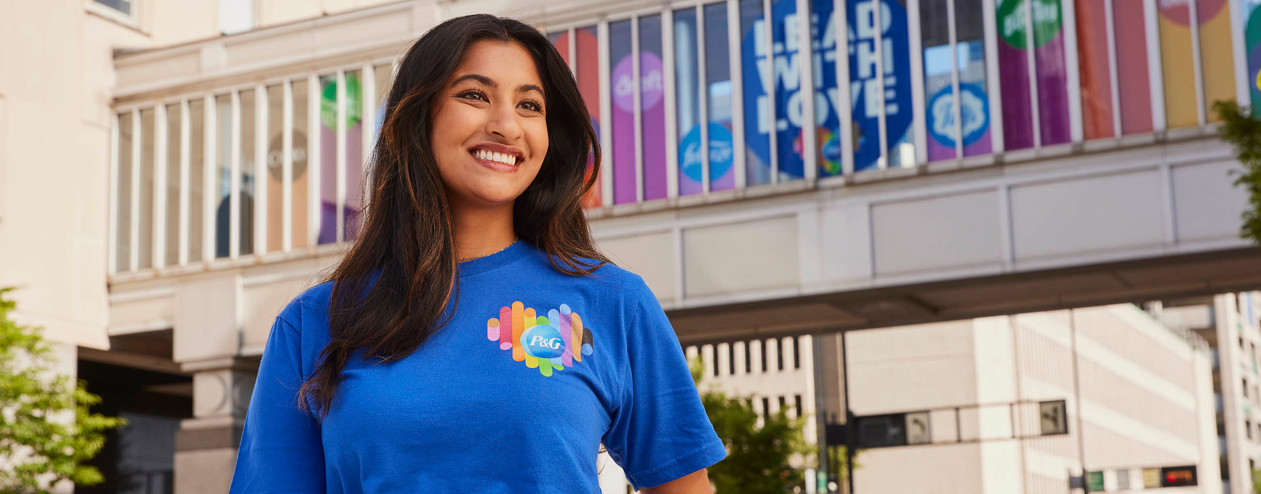 Girl in blue P&G shirt smiling with rainbow bridge in background