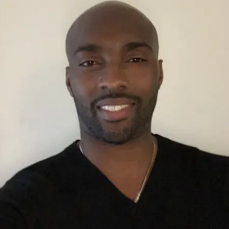 A young man in a black t-shirt smiles.