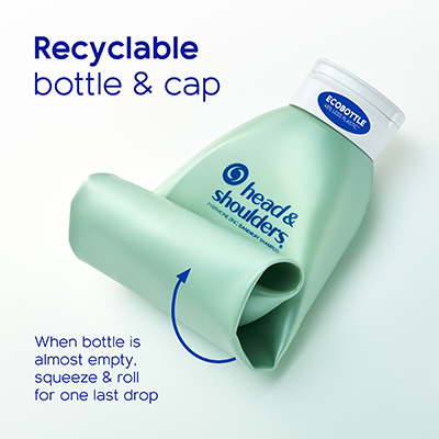 A light green Head & Shoulders shampoo bottle with a white cap. The bottle is rolled all the way up. Blue text reads "Recyclable bottle & cap. When bottle is almost empty, squeeze and roll for one last drop."