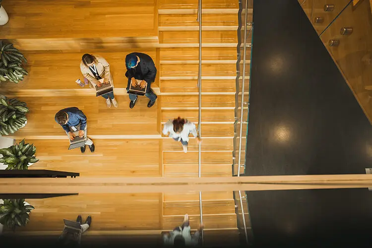 Birds eye view of P&G employees sitting on stairs using their laptops.
