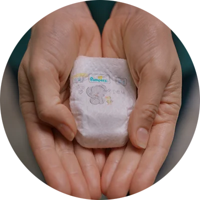Cupped hands holding the Pampers Swaddlers Pxxs diaper.