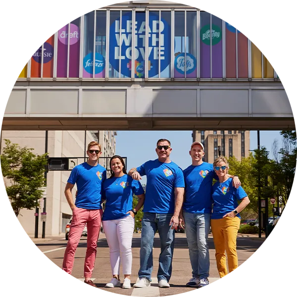 Five members of P&G’s “GABLE employee resource group stand in front of a bridge with a sign that reads, “Lead with Love.”