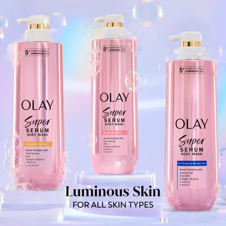 Three pink bottles of OLAY Super Serum Body Wash in front of a light purple background with bubbles floating around the product. Text reads: Luminous Skin for all skin types.