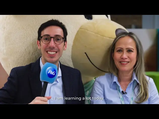 Man interviewing a woman, both looking towards the camera