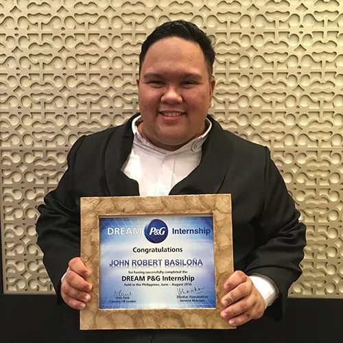 A smiling young man proudly shows his P&G internship completion certificate.