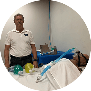 Man standing above a dummy wearing a breathing mask