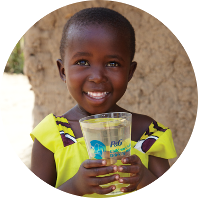 A young black girl in a bright yellow dress smiles as she holds a plastic cup of water.