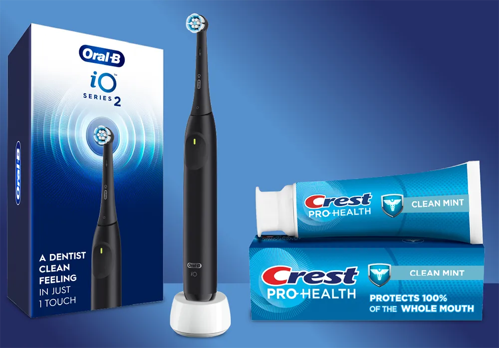 A black electric toothbrush and its packaging are displayed alongside a tube and box of clean mint toothpaste, all against a blue background.
