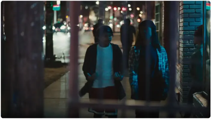 Screenshot of the video Widen the Screen showing 2 people walking on the street at night. 
