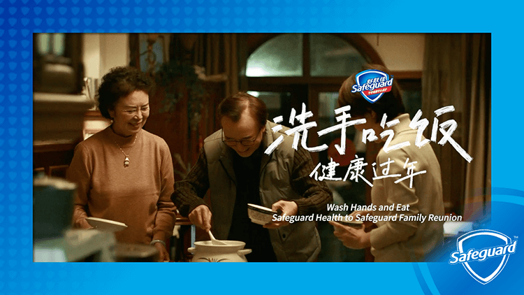 Two adult Chinese women with short brown hair, and an adult Chinese man with short brown hair and glasses, stand over a large pot at the kitchen table.