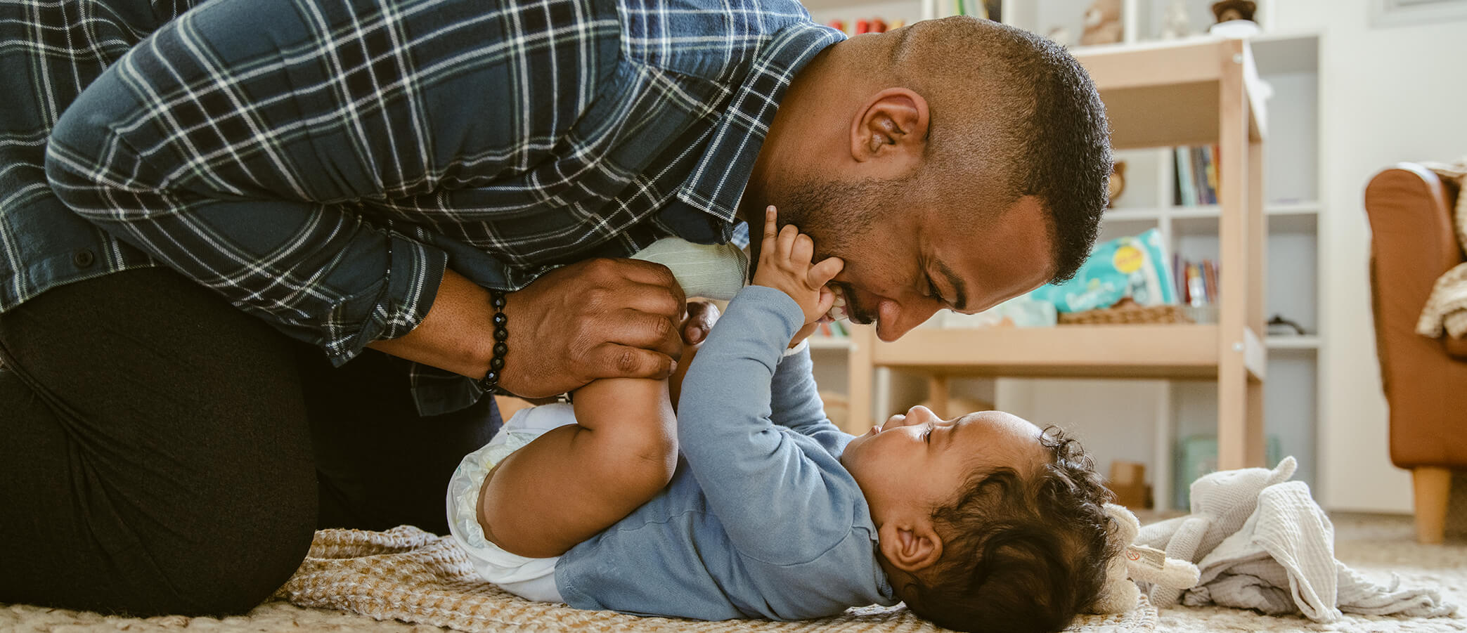 A father leans over and plays with his baby.