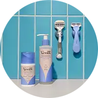 Venus razor and shaving gel bottles with pastel packaging displayed against tiled wall hooks