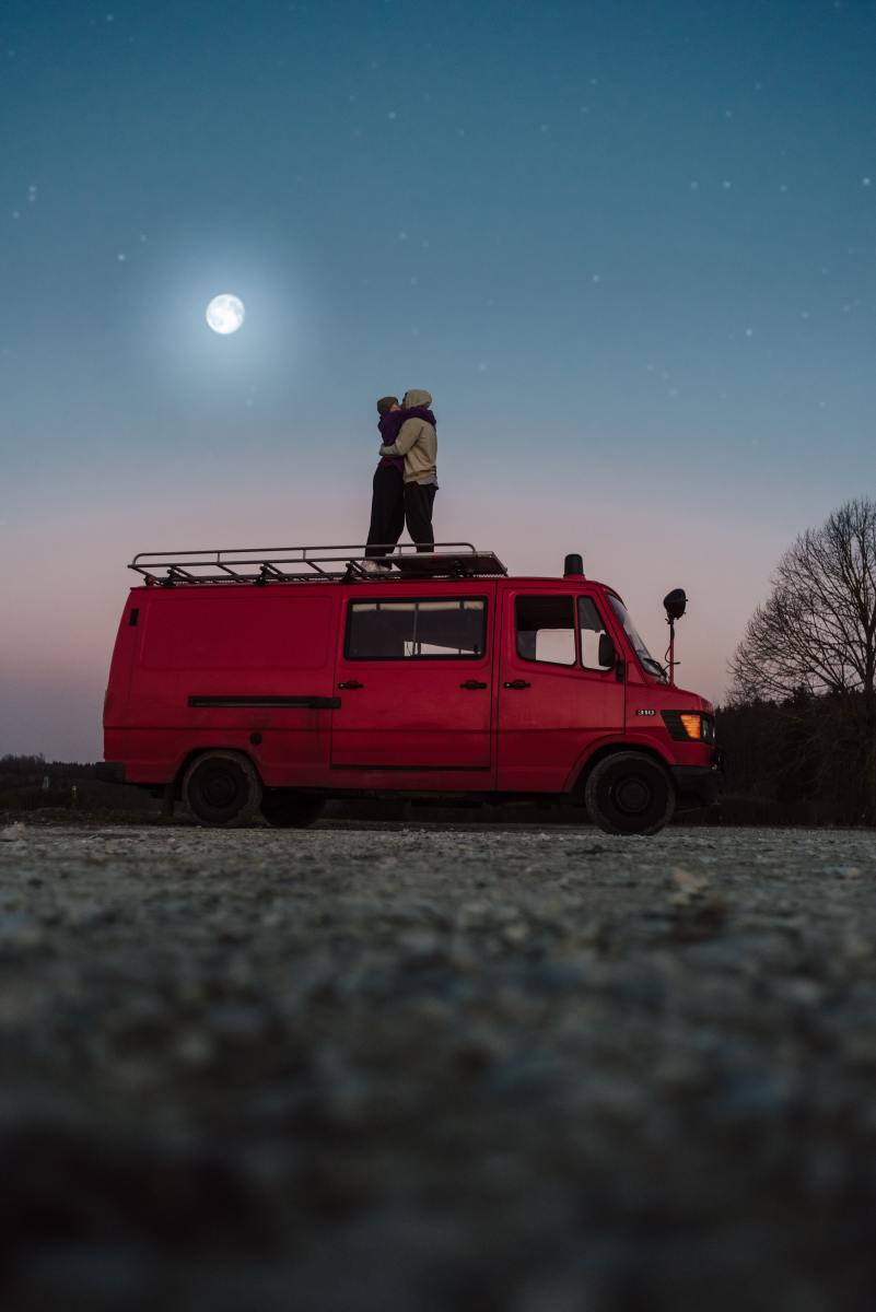 vanlife couple on top of van